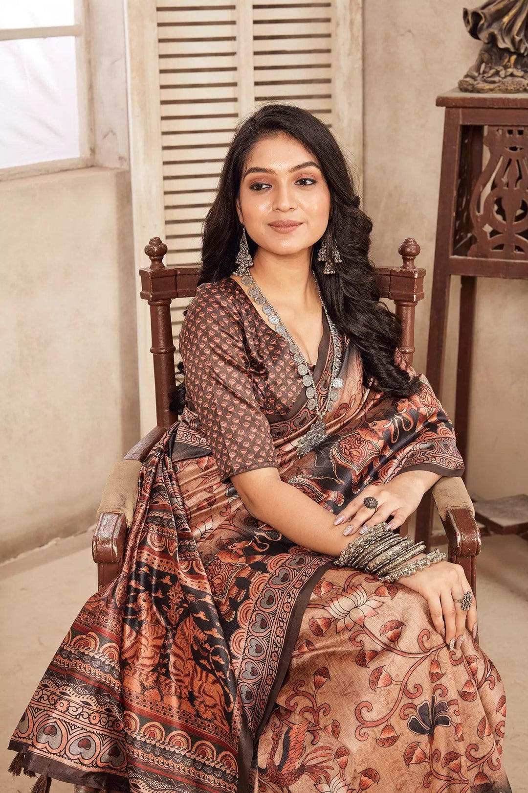 woman sitting on chair in Traditional Kalamkari Figer Diya Saree.