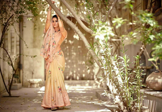 woman standing with tree branch in floral yellow gradient crochet saree.