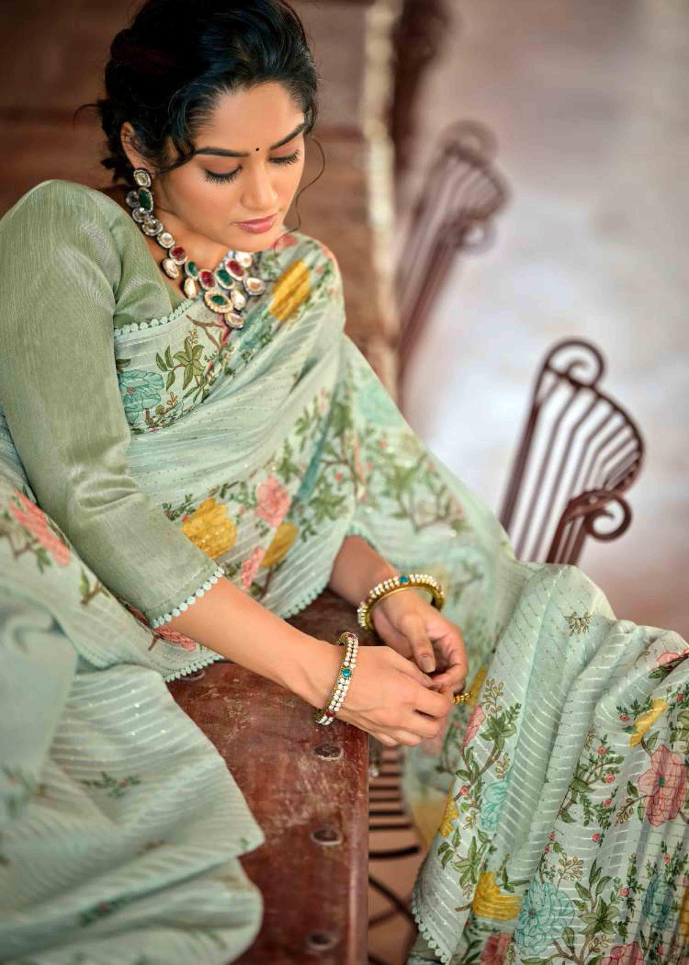 Woman in floral jal crochet saree sitting on bench.