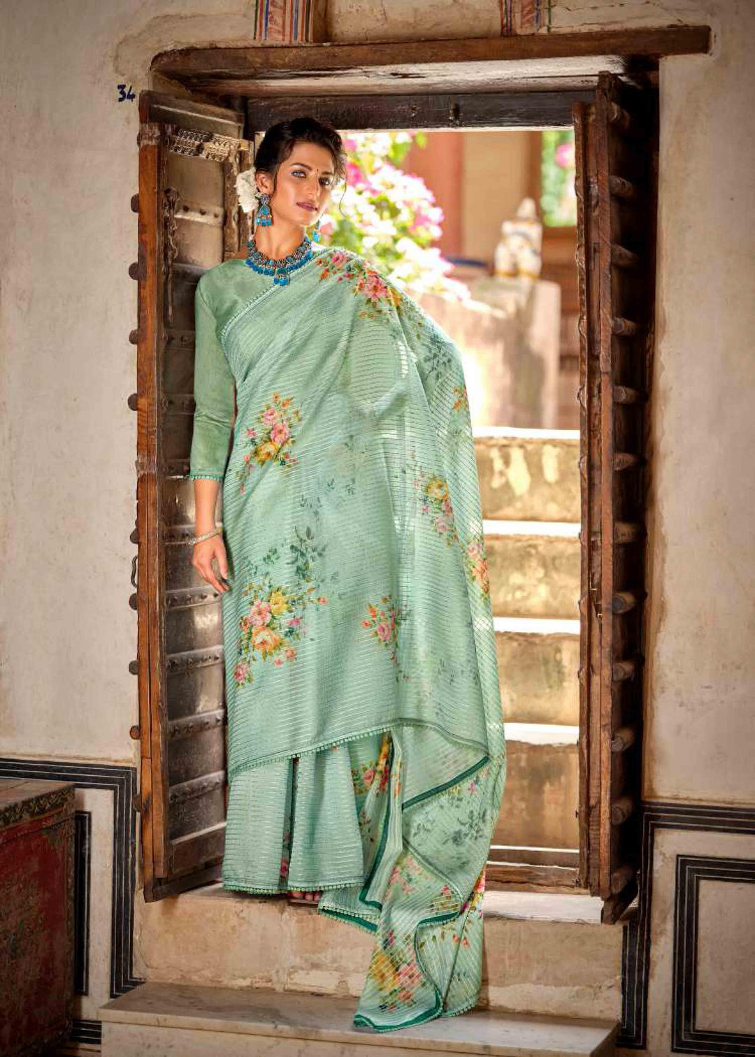 woman standing on door in green floral crochet saree.