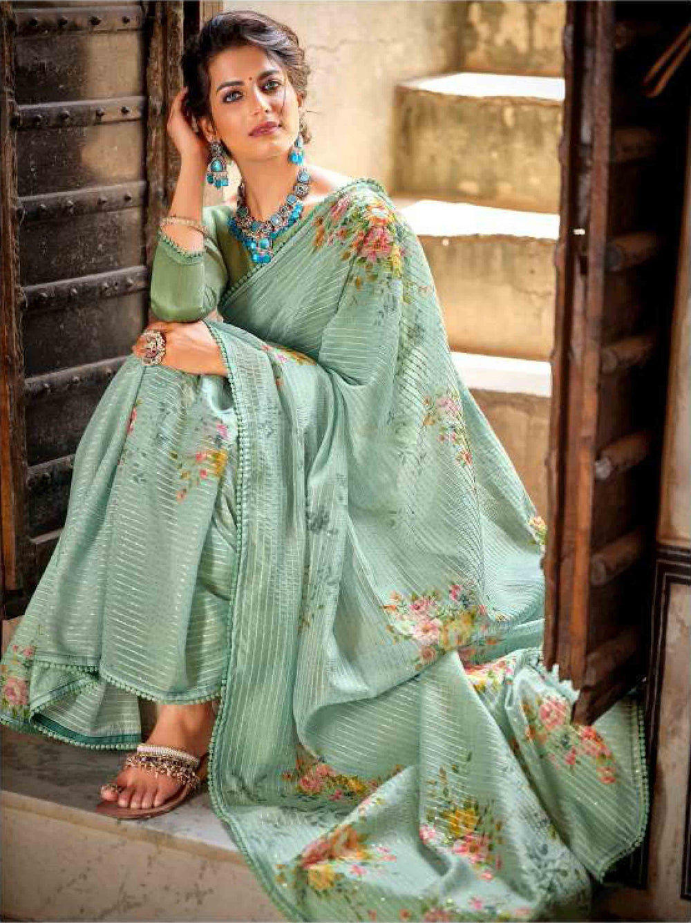 woman sitting on door in green floral crochet saree.