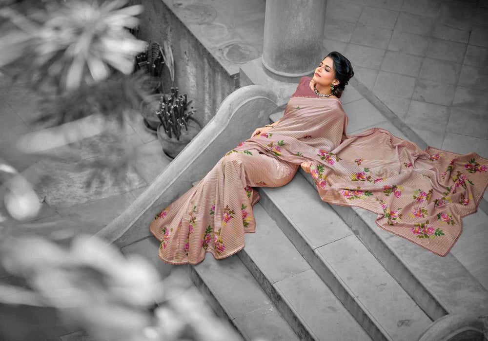 A woman in a floral crochet saree sitting gracefully on steps.